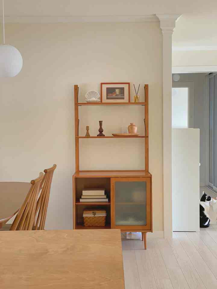 Natural wood tone and beige wall kitchen featuring wooden cabinet and dining chairs arranged neatly in a cozy space