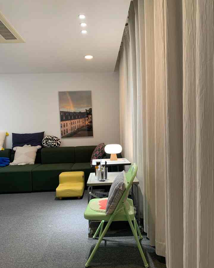 Living room with dark green sofa, yellow pet steps, and floor-to-ceiling curtains creating a cozy atmosphere