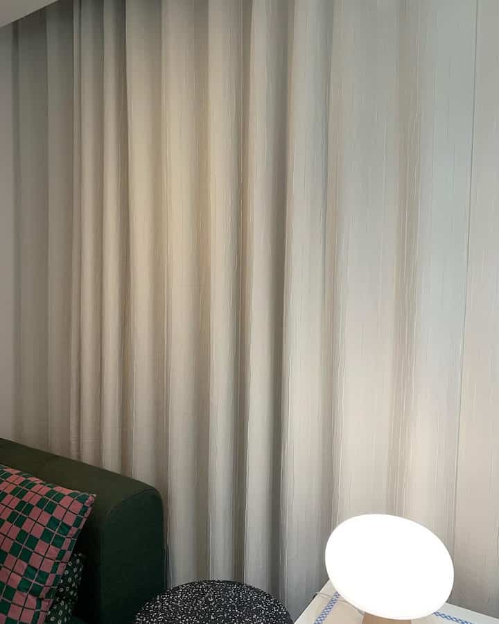 Beige-toned living room featuring dark green sofa and blackout curtains with a natural atmosphere