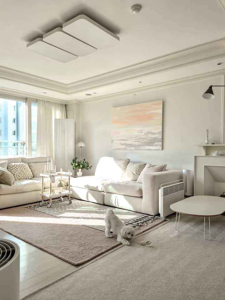 Bright white and beige toned Nordic living room featuring large sofa and rugs with warm natural atmosphere