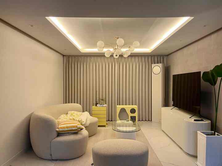 White and yellow toned living room featuring a rounded sofa and cat furniture with a modern, cozy atmosphere