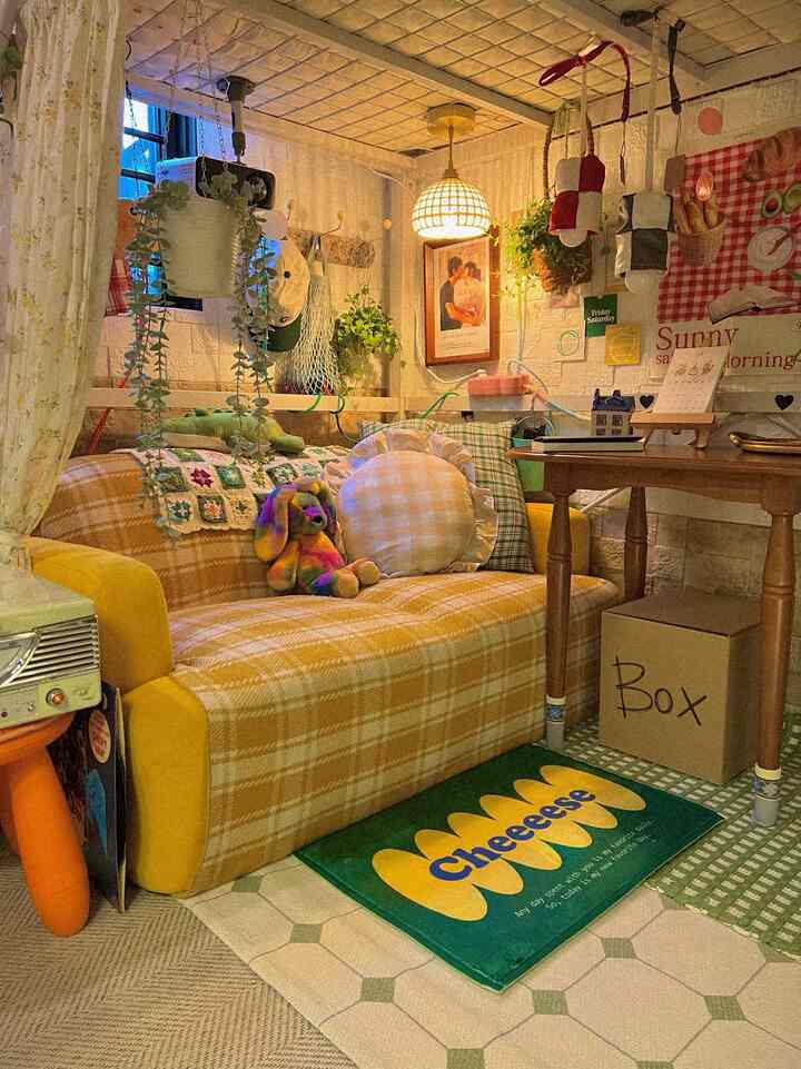 イエローチェックのソファとグリーンのバスマットが配置されたヴィンテージ風の小さなリビングスペース