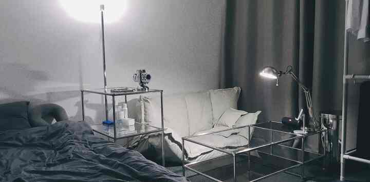 モダンなシルバーのメタルフレームとグレーのトーンの寝室、ホワイトのソファとベッドが配置された落ち着いた空間