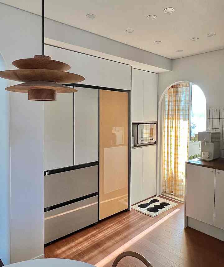 Modern natural kitchen with white walls and yellow check curtain by an arched doorway