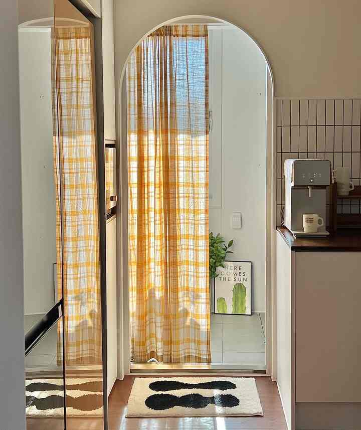 Small simple space with yellow checkered curtain and neat kitchen area