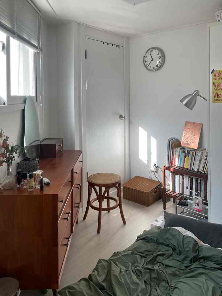 White-walled studio bedroom featuring vintage wood furniture and natural elements with cozy atmosphere