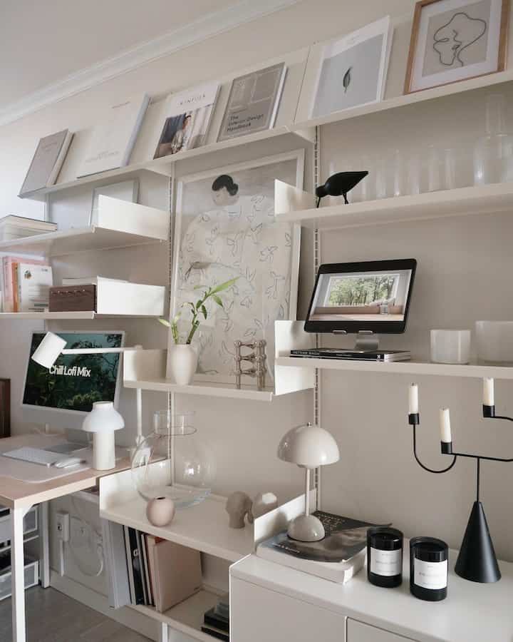 White and beige toned study and home office space featuring clean desk, shelves, and minimalist lighting in a neat interior