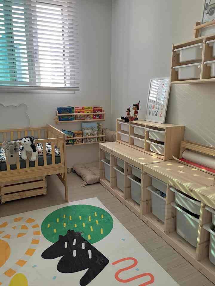 Natural-toned kids' room with white walls, featuring a wooden crib and multi-compartment storage units in a tidy layout