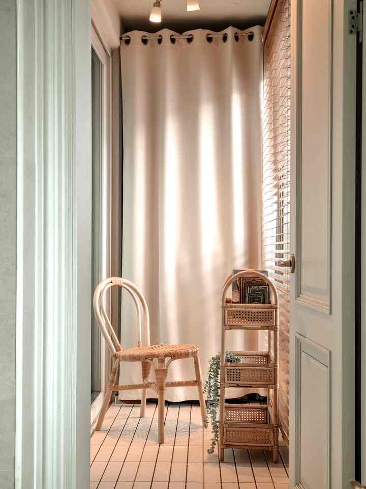 Compact veranda interior with beige blackout curtain and natural wood furniture creating a cozy atmosphere