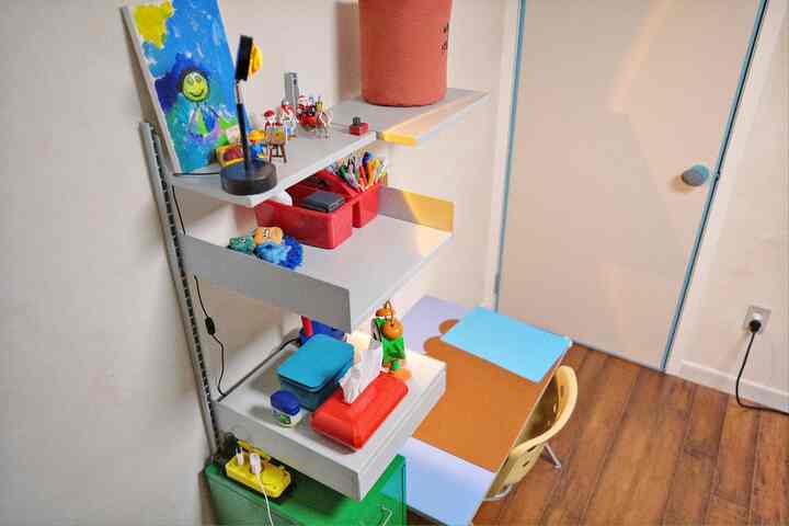 Light brown and white toned kids' room featuring a desk and shelves with organized storage, clean atmosphere