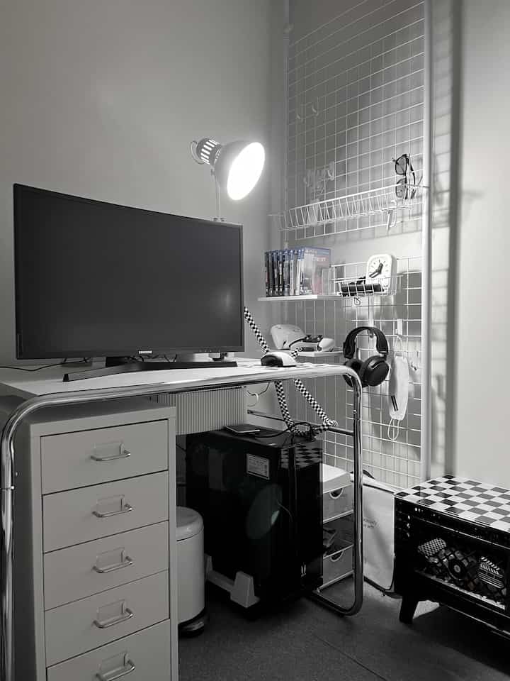 モノトーンの小さなホームオフィス空間、デスク、引き出しキャビネット、白いグリッドシェルフが整然と配置された作業スペース