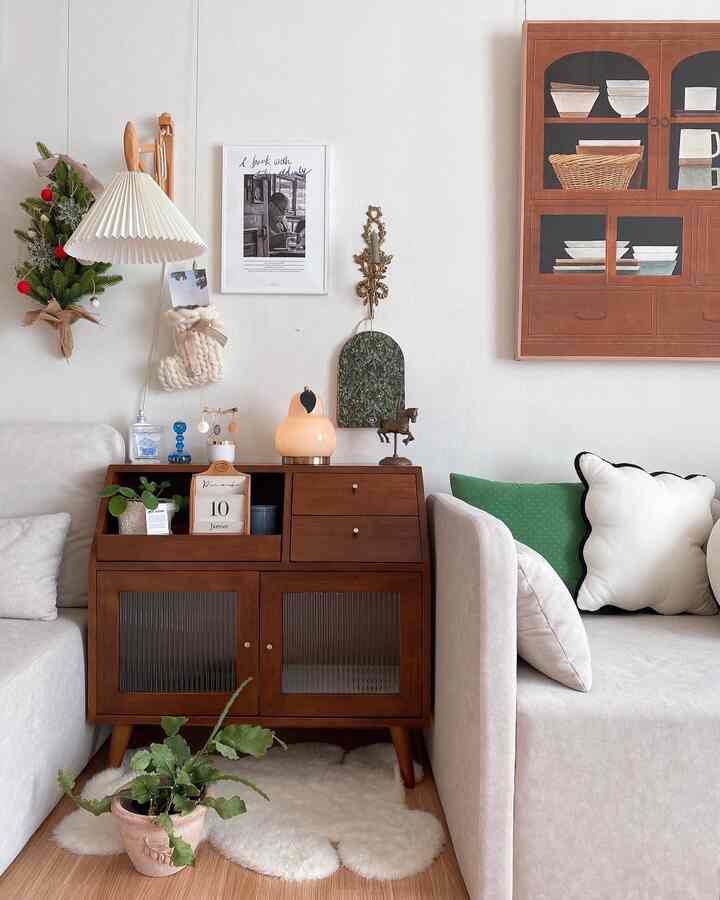 Natural color and white-walled living room featuring Medio wood tall cabinet, sofas, and plants creating a cozy space