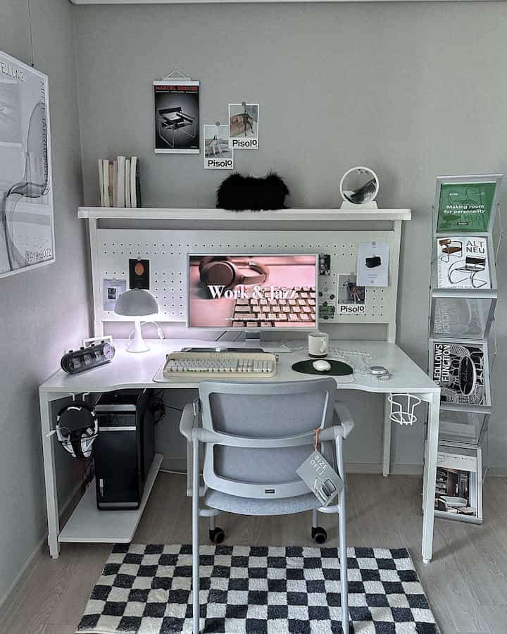 Bright white and gray toned home office space featuring a modern desk, office chair, posters, and bookshelf in a simple workspace