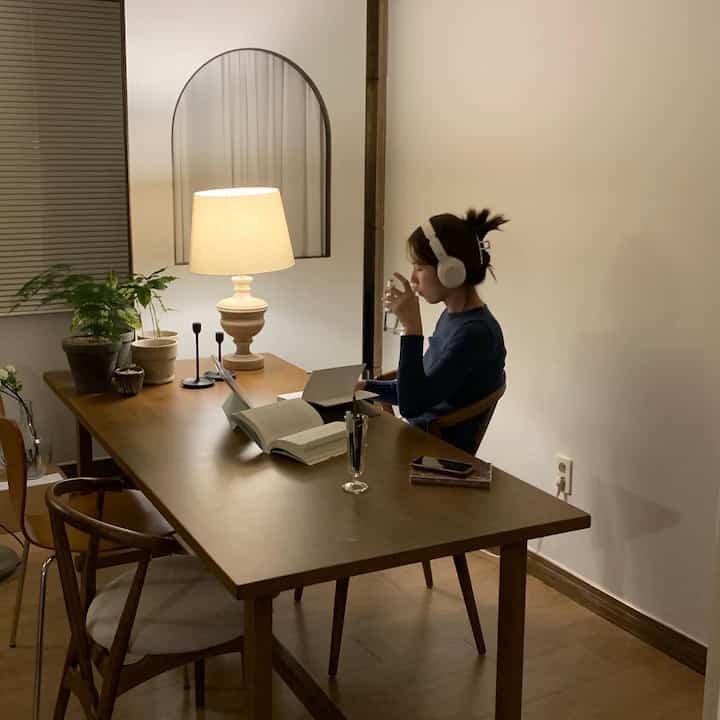 Natural wood-toned living room featuring a wooden dining table and chairs in a cozy reading and journaling space