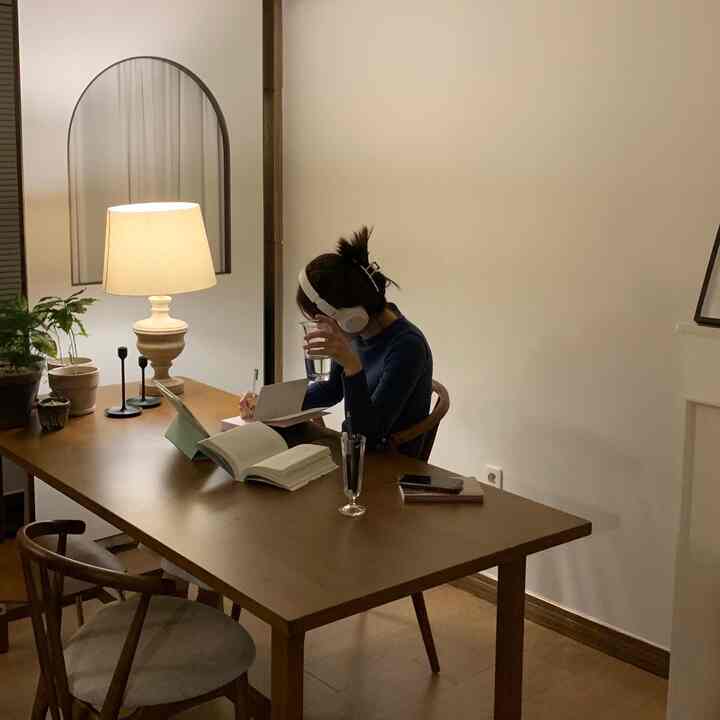 Warm wood tone natural dining room, person working remotely at table doubling as a desk