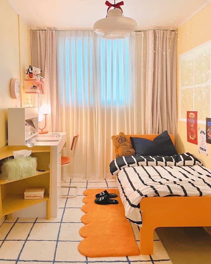明るく温かみのあるオレンジとホワイトの色調の子供部屋、机とベッドが配された印象的な空間
