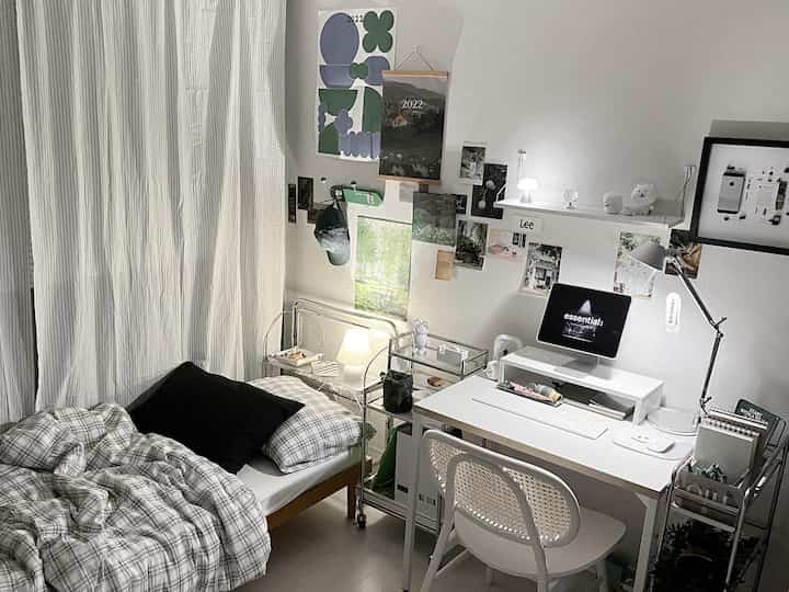 ホワイトトーンのモジュール家具とシンプルな机が配置された一人暮らし向けのモダンな寝室兼ホームオフィスの空間