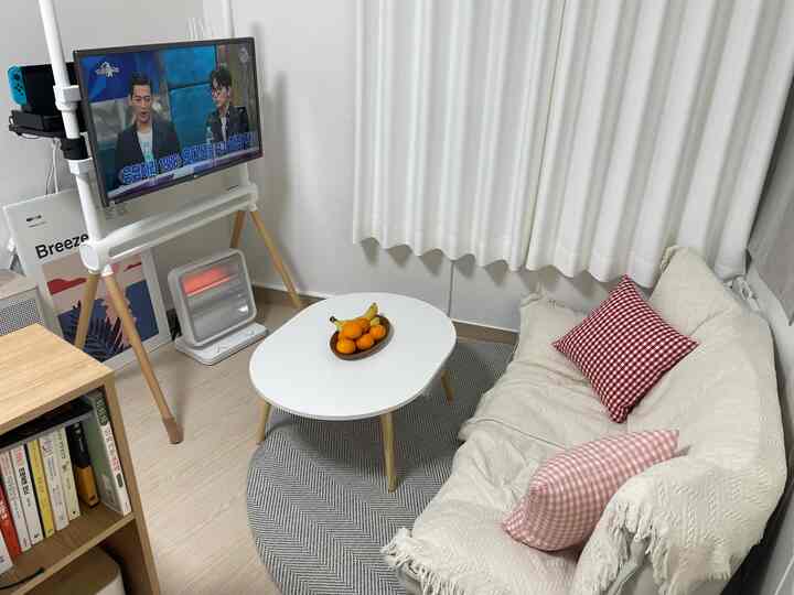 A white and wood tone 6-pyeong studio living room featuring a floor sofa and oval table with a cozy atmosphere