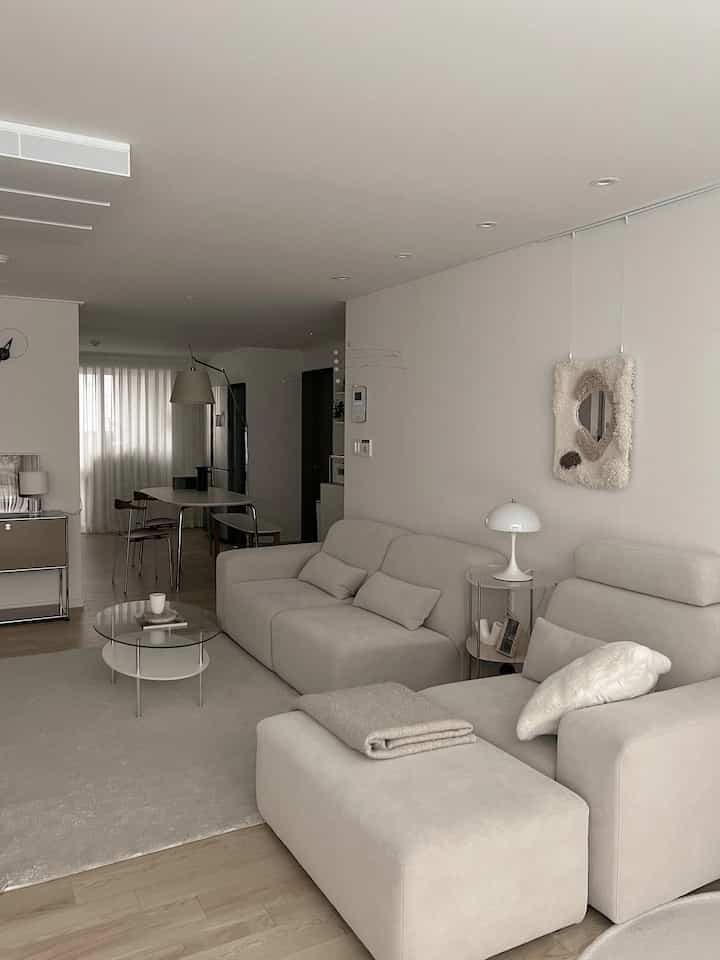 Beige and white toned living room featuring simple sofas and a glass coffee table with a natural, calm atmosphere
