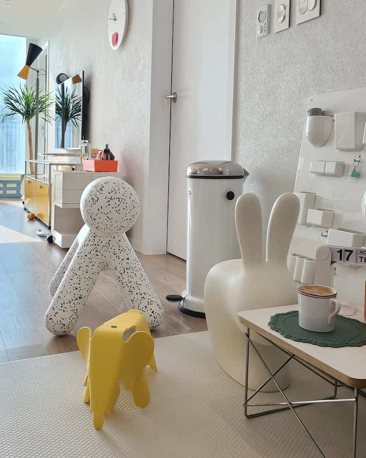 White and natural wood-tone small living room featuring playful designer chairs and storage objets arranged cozy