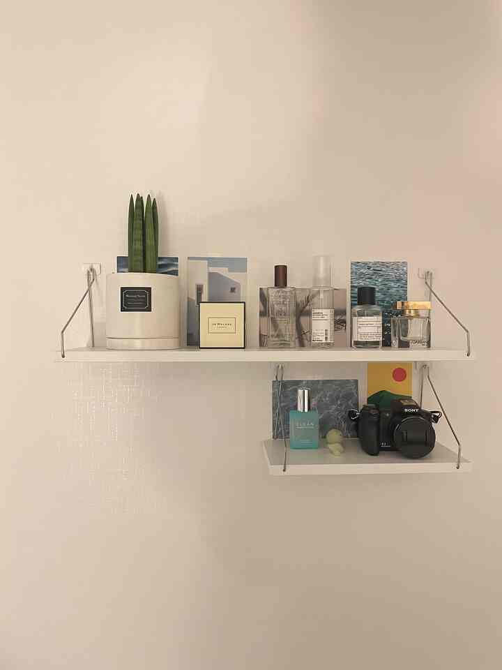 白い壁と棚が配置されたミニマルでナチュラルな玄関、植物がアクセントとなっている雰囲気のあるインテリア