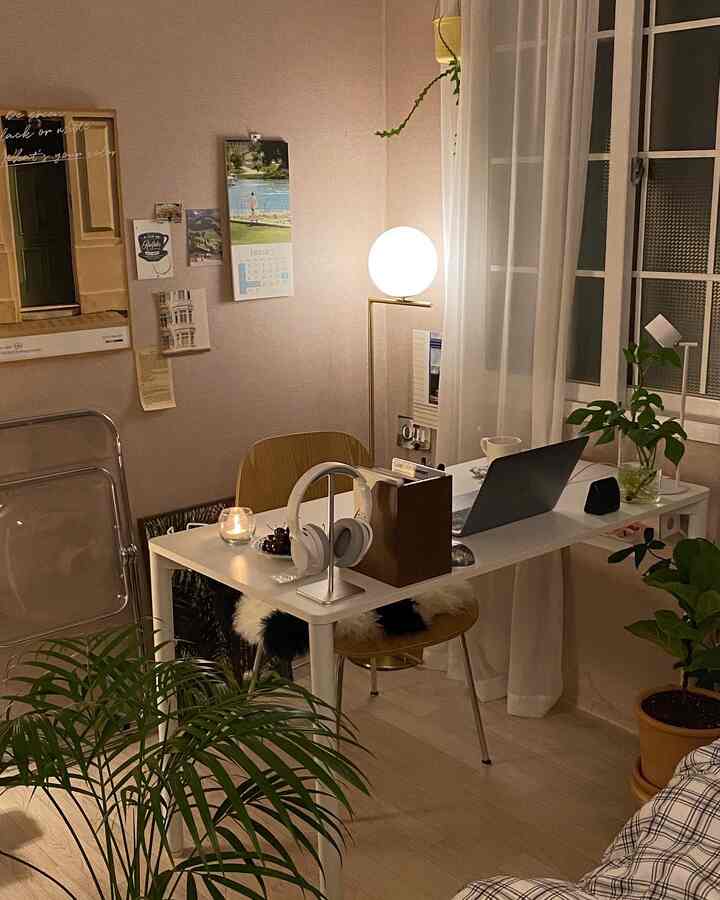 White and wood tone home office featuring a desk, floor lamp, and plants creating a cozy, focus-friendly study interior