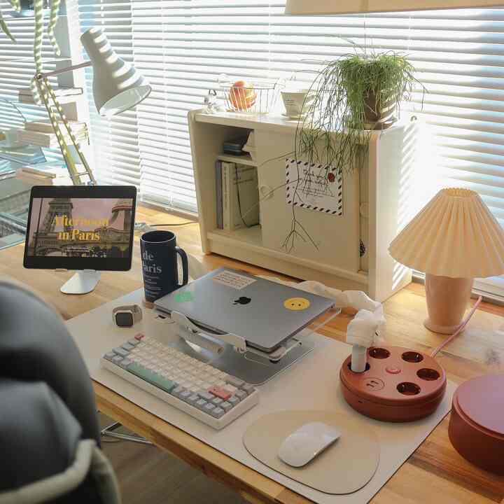 Bright home office with white and natural wood tones, featuring a laptop, keyboard, and plants on a tidy desk