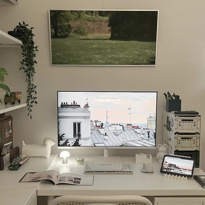 White-toned computer workspace featuring a large monitor, iPad, keyboard, and mouse neatly arranged on a simple desk
