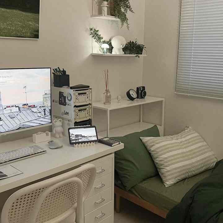 Small studio home office with white and green tones, featuring a simple tidy bed and desk arrangement