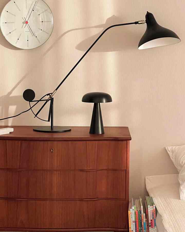 Natural color wall and wooden dresser featuring two black table lamps in a cozy bedroom corner