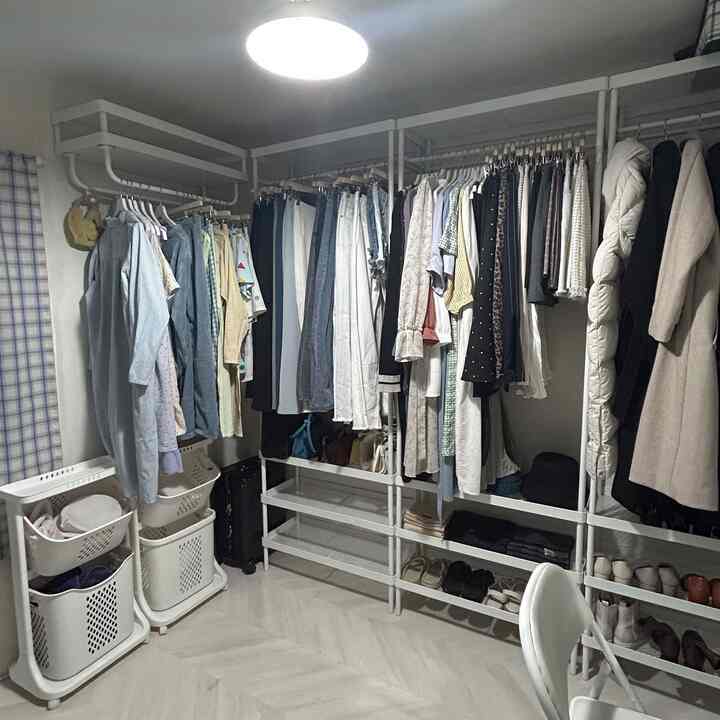 White-toned compact closet featuring IKEA coat racks and shoe storage with organized layout