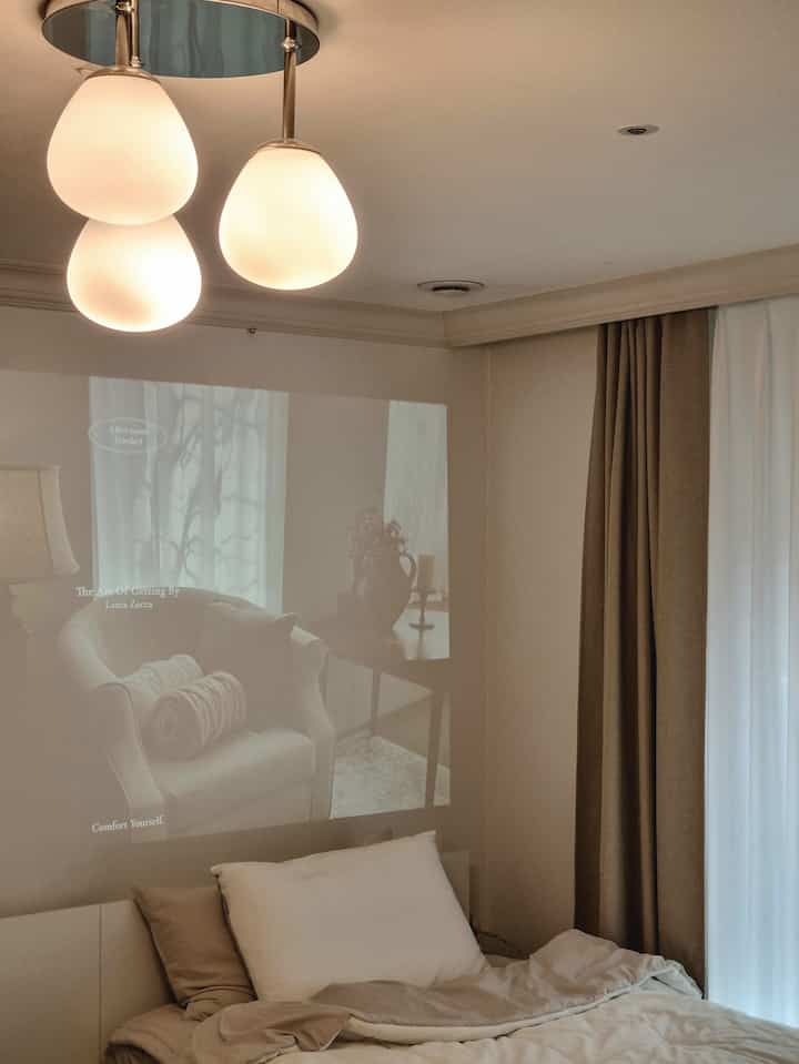 Cozy bedroom in warm brown and white tones featuring soft glowing ceiling lights and linen curtains