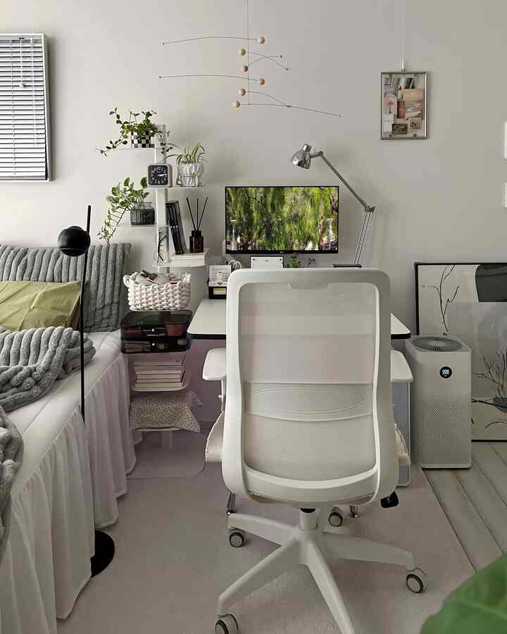Bright white-toned home office space with desk, office chair, gray sofa, and plants arranged for a cozy atmosphere