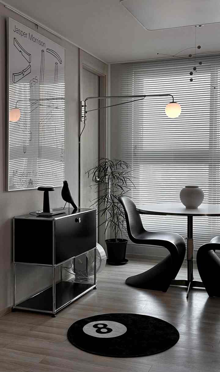 黒と白のトーンのモダンなリビング、黒いキャビネットと曲線の椅子、円形のラグが配置されたシンプルなインテリア