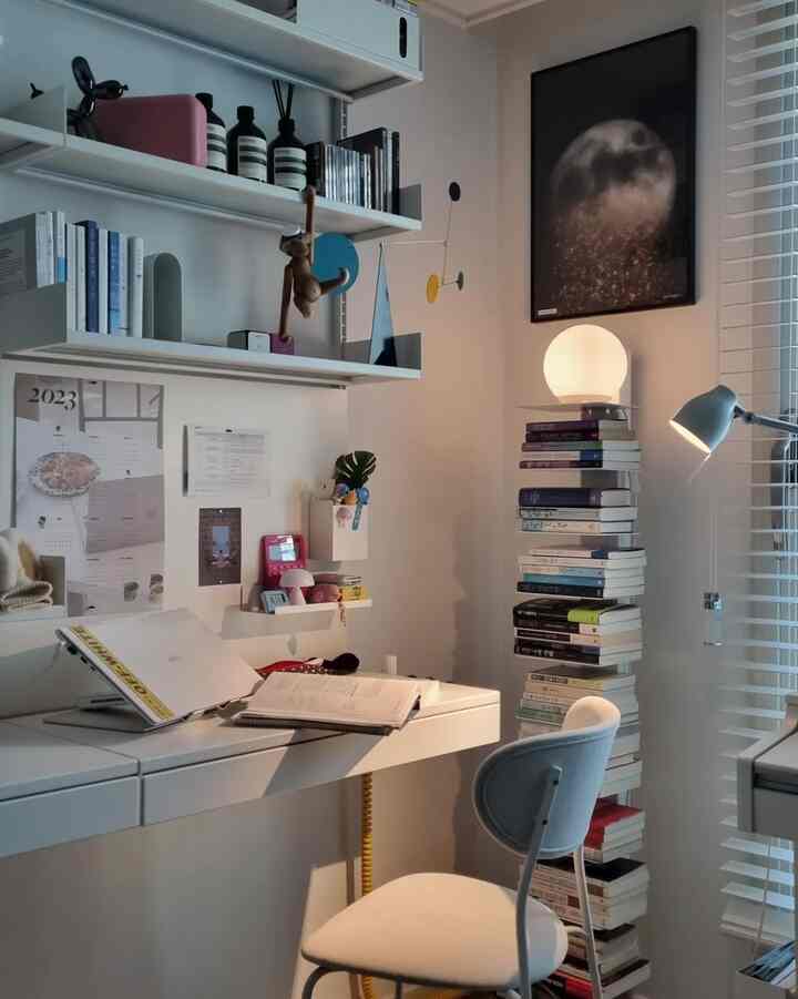White and gray toned study with desk, chair, lighting, and shelves arranged in a cozy modern workspace