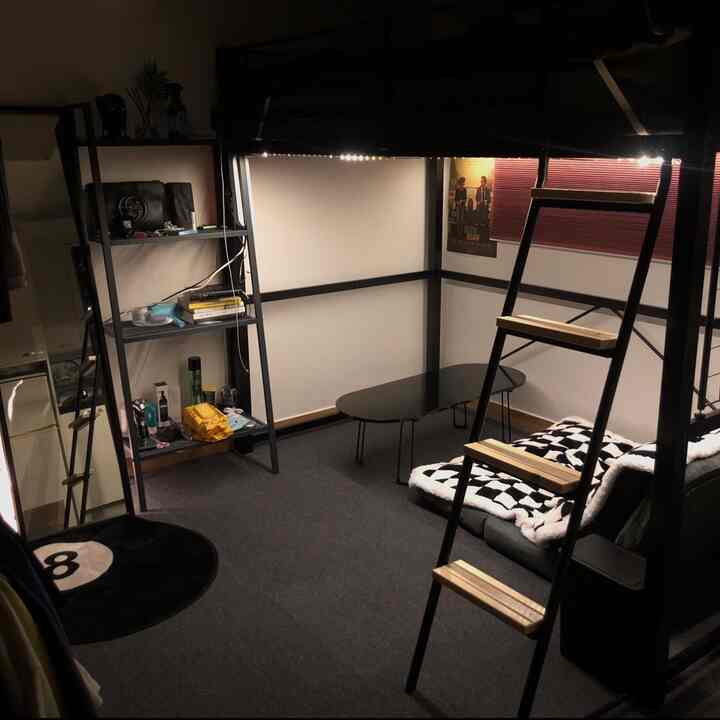 黒とグレーのトーンのワンルーム、バンカーベッドと棚、ローテーブルが配置されたモダンでコンパクトなインテリア