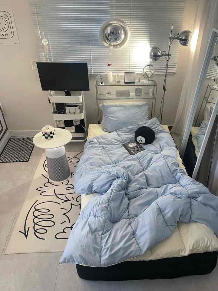 Small bedroom in white and blue tones featuring a bed with blue bedding and modern furniture arranged neatly