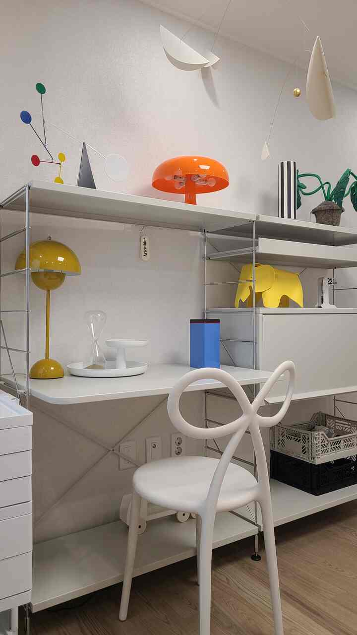 白と黄色を基調とした子供部屋、デスクと椅子、多彩なモビールが配置された明るく清潔感のあるインテリア