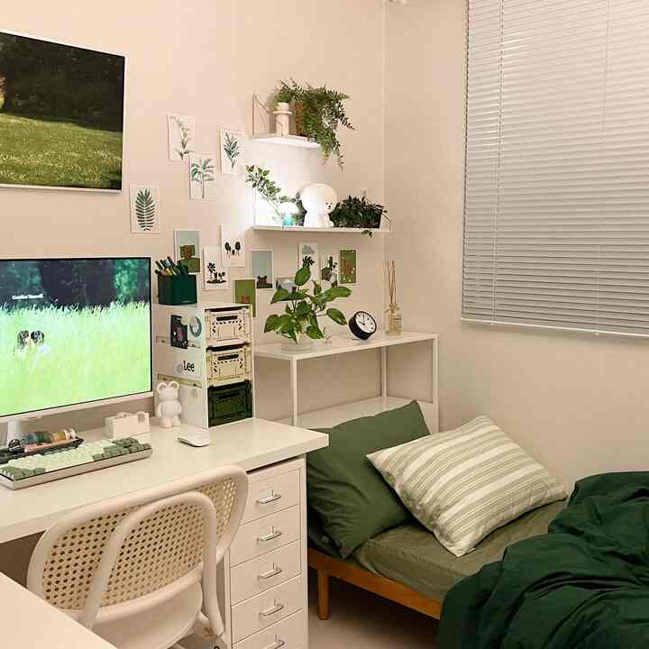 ホワイトとグリーンのトーンが印象的な寝室兼ホームオフィス、整ったデスクやポスター、植物が配置された落ち着いたインテリア