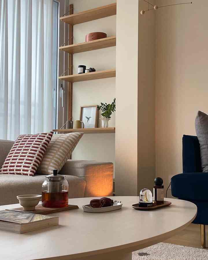 Beige and navy toned living room with round coffee table and wooden shelves, cozy natural atmosphere