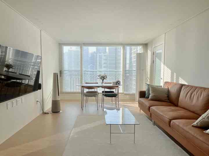 Beige-toned modern living room featuring leather sofa, dining table, and coffee table with bright, clean atmosphere