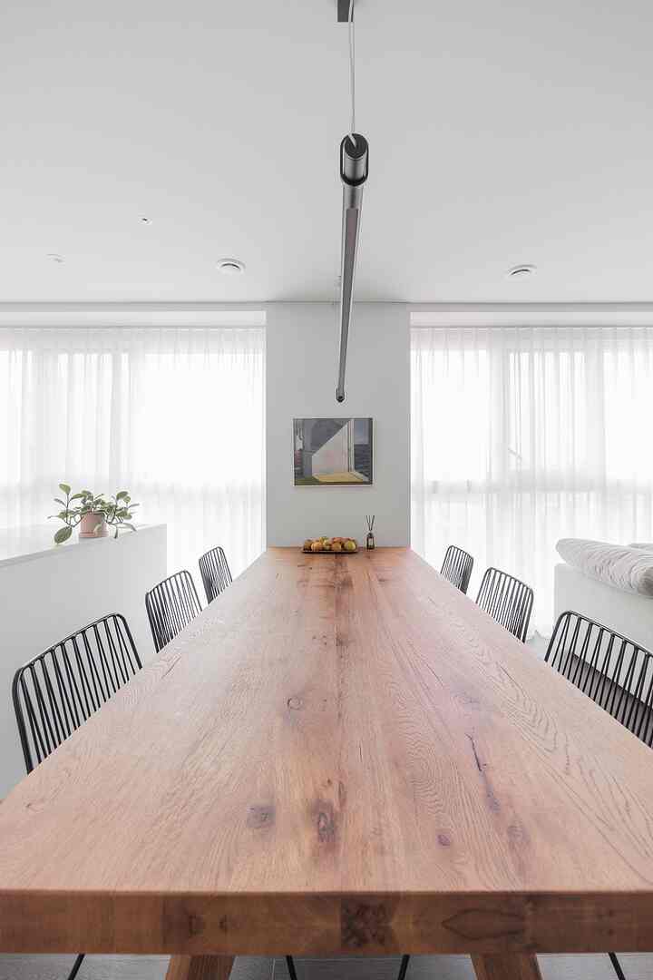 Bright white-toned dining room featuring a large solid wood 6-person dining table with black metal chairs and an Edward Hopper painting on the wall