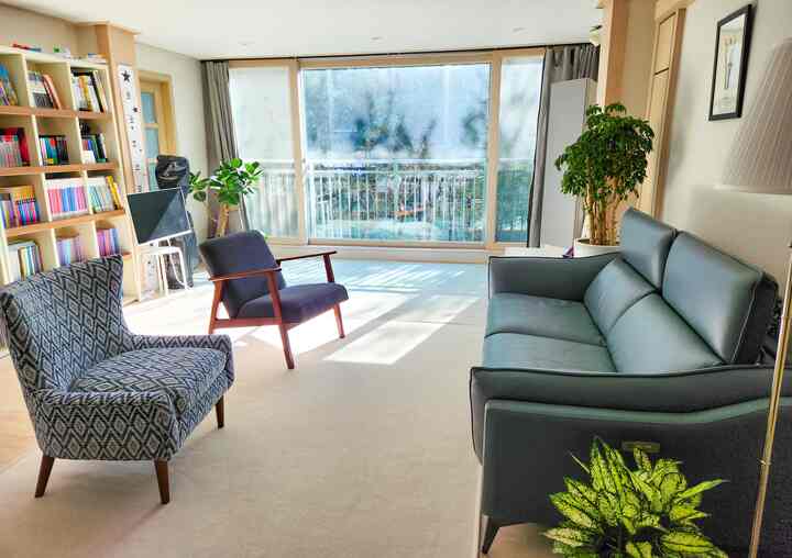 Natural toned living room bathed in bright natural light, featuring sofa and armchairs arranged comfortably