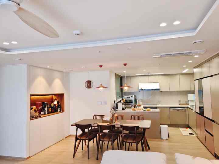 白と木目調が調和する、6人掛けのダイニングテーブルとキッチンが配置されたモダンなダイニングルーム