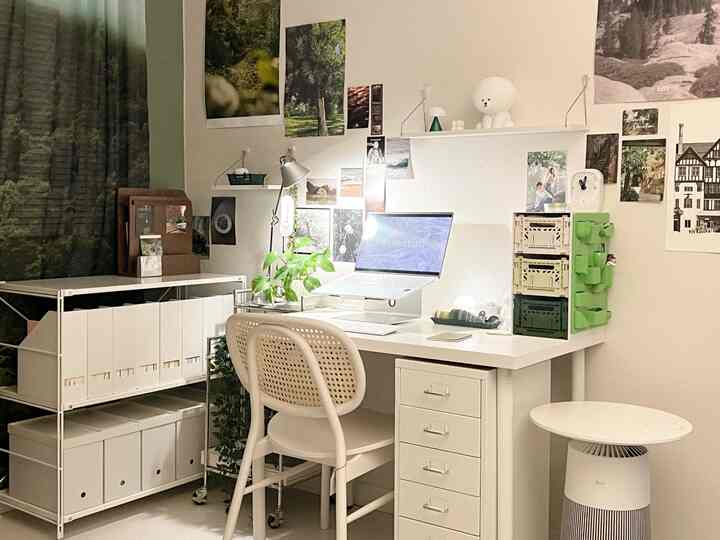 白を基調としたホームオフィス、すっきりしたデスクと本棚、ノートパソコンと植物が配置された落ち着いた雰囲気のインテリア