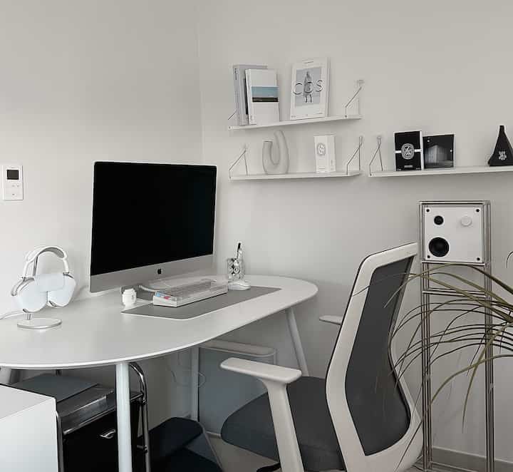 White and gray toned studio home office featuring an iMac and AirPods Max on a tidy desk workspace