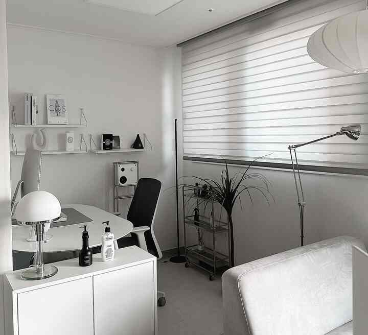 White tone home office space featuring a simple modern desk and sofa with a clean minimalist interior
