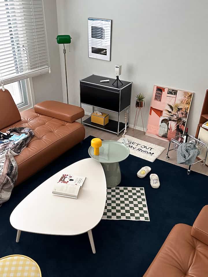 Natural modern living room with brown leather sofas, navy rug, and white coffee table, featuring minimalist decor
