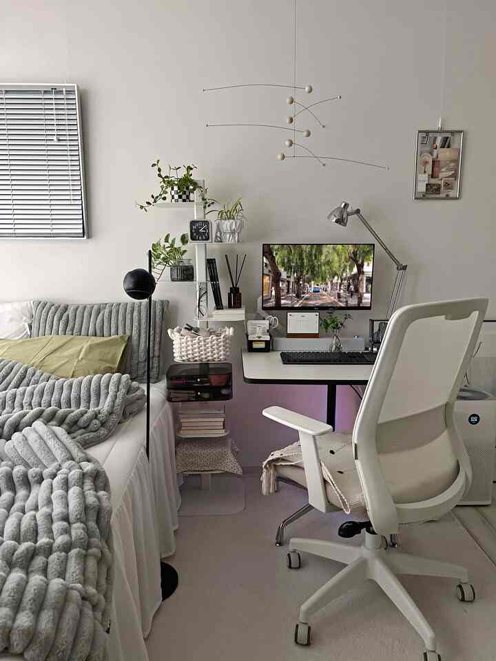 White and gray toned studio bedroom featuring bed and home office desk in a clean, simple space