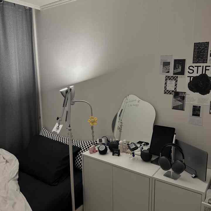 モノトーン調の小さな寝室、黒い寝具とチェッカーボードのクッション、ホワイトEKETキャビネットが配置された清潔でシンプルな空間